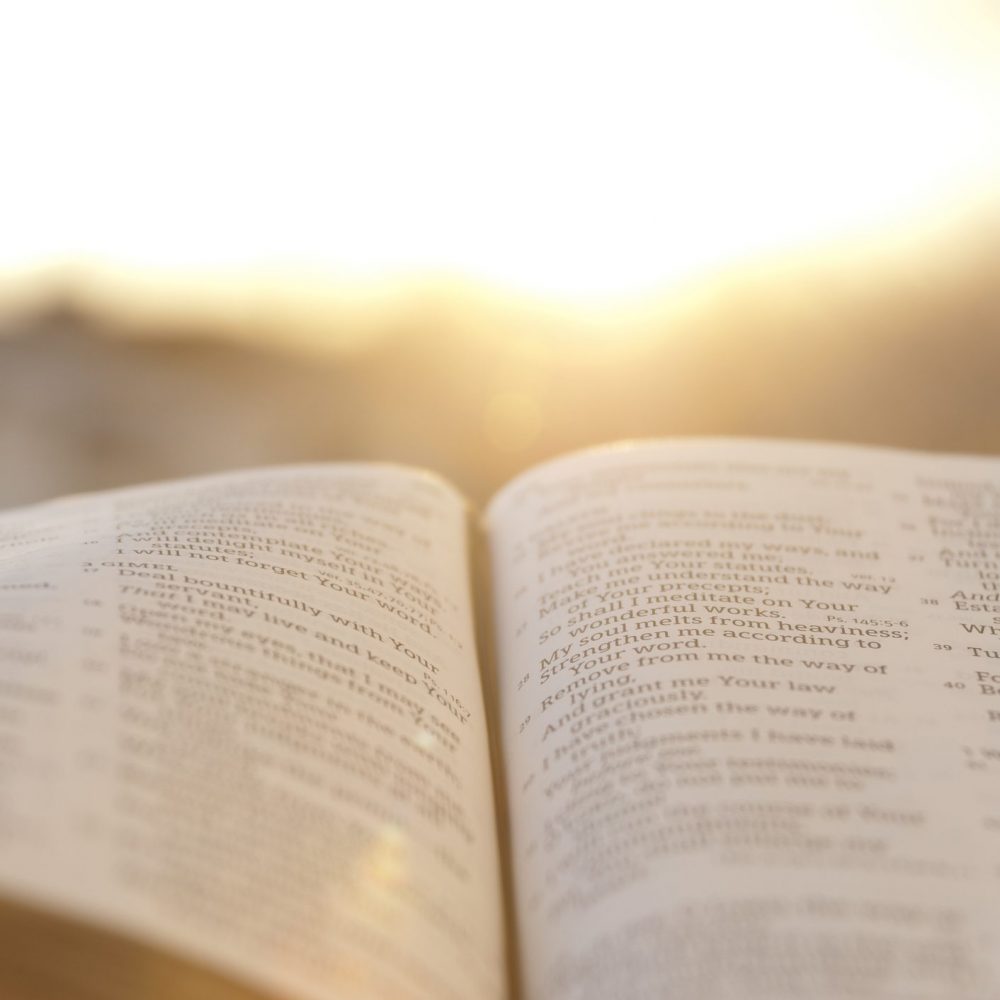 Open Bible with bright sunset in the background.